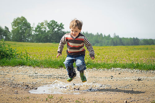 Boy jumping into a puddle